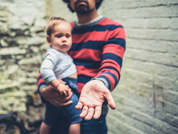 A young man with spots on his hands from disease is begging with a baby outside