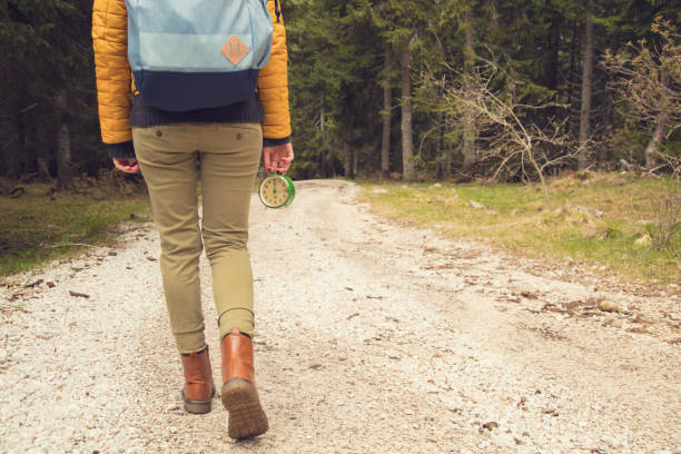 Girl holding a vintage old clock on a empty dirt-road.
