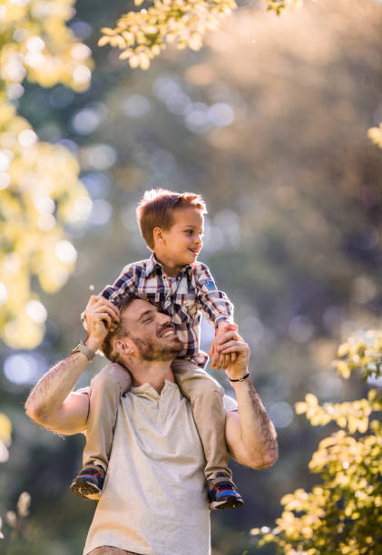 istock Playful father having fun with his son while carrying him on shoulders in nature. 923184614
