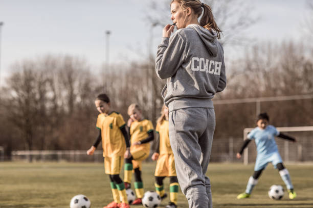 young blonde weibliche fußball-trainer und ihre mädchen-fußball-nationalmannschaft - coach stock-fotos und bilder