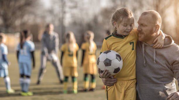 w średnim wieku ruda ojciec i blondynka córka coaching piłki nożnej razem do drużyny girl football - long hair red hair women men zdjęcia i obrazy z banku zdjęć