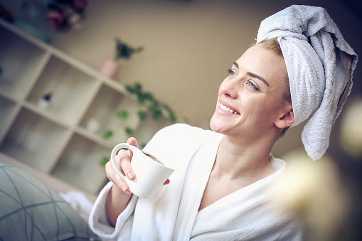 Smiling woman at home holding cup of coffee. Close up.