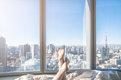 people Relaxing in the hotel room in the Morning sunshine on the bed with tokyo city skyline scenery outside the window