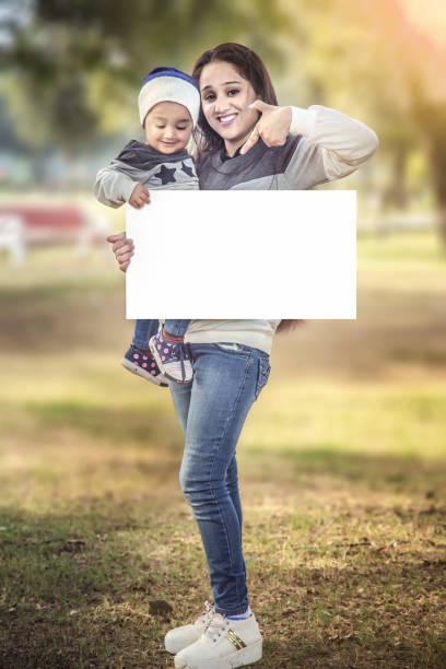 mother and daughter holding a white board - outdoors playing family spring imagens e fotografias de stock