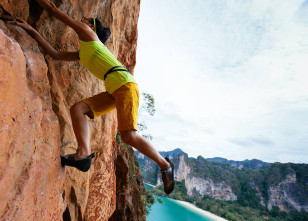 istock female rock climber climbing on seaside cliff 923216232