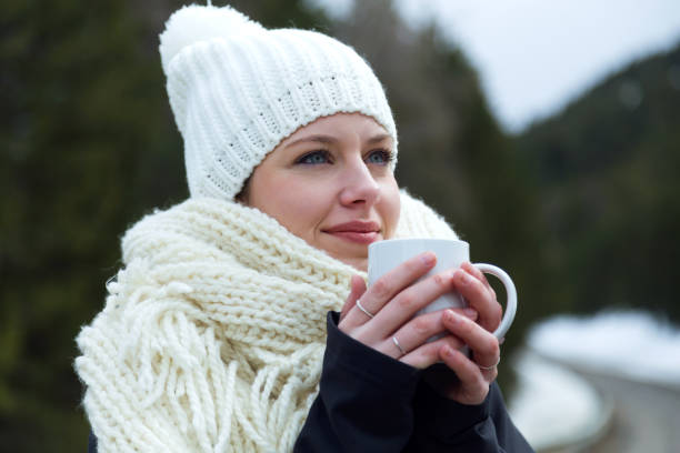 istock Beautiful young woman drinking coffee over winter background. 923217290