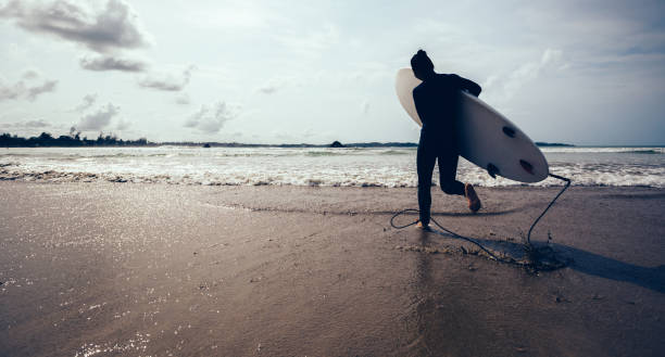 istock woman surfer with surfboard running on beach 923217330