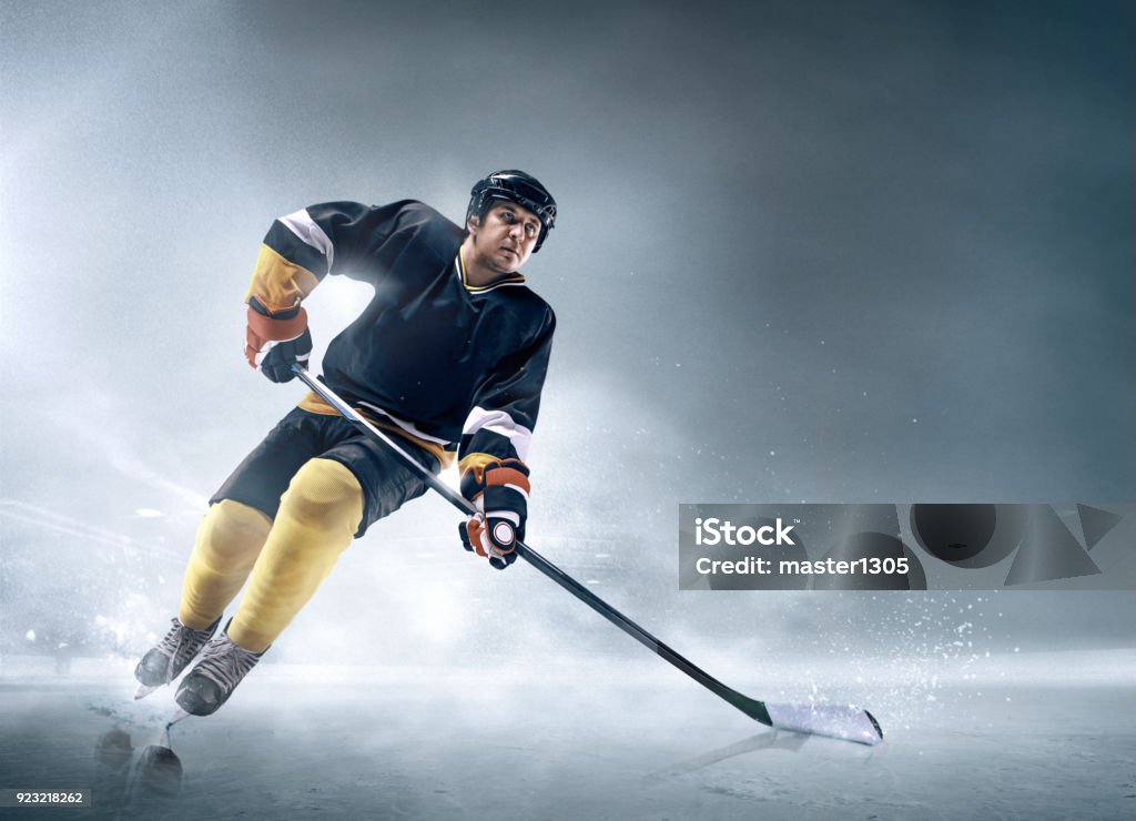 Ice hockey player in action Decisive throw of the puck and goal. Ice hockey player in action on ice. Male professional athlete swinging his stick before a decisive blow. Tension and rage. Sports emotions. Motion and movement. Hockey Stock Photo