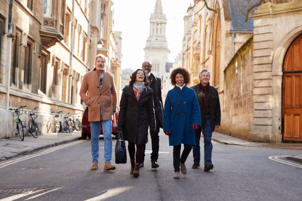 gruppo di amici maturi che camminano per la città in autunno insieme - town of friendship foto e immagini stock