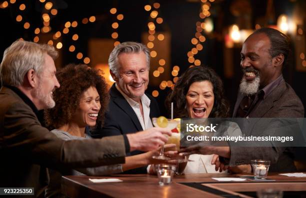 Group Of Middle Aged Friends Celebrating In Bar Together Stock Photo - Download Image Now