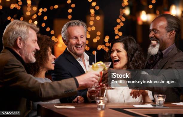 Group Of Middle Aged Friends Celebrating In Bar Together Stock Photo - Download Image Now