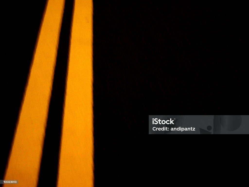 Solid yellow dividing lines on a dark black pavement  Asphalt Stock Photo