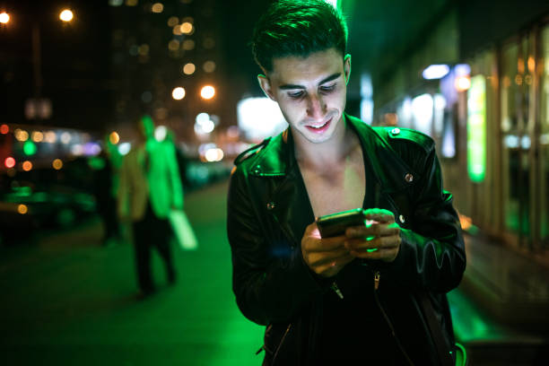 istock Young man using smart phone in city street at night 923233308