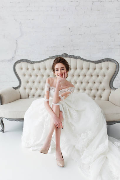 istock Beautiful, elegant bride sitting on vintage sofa in white nterior with brick wall background 923236994