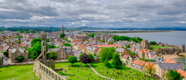 the town of st andrews seen from the st rule's tower. you can see the ruins of the cathedral, built in 1158, and the ruins of the castle, dating to the 1200s. st andrews, fife, scotland. - uk cathedral cemetery day imagens e fotografias de stock