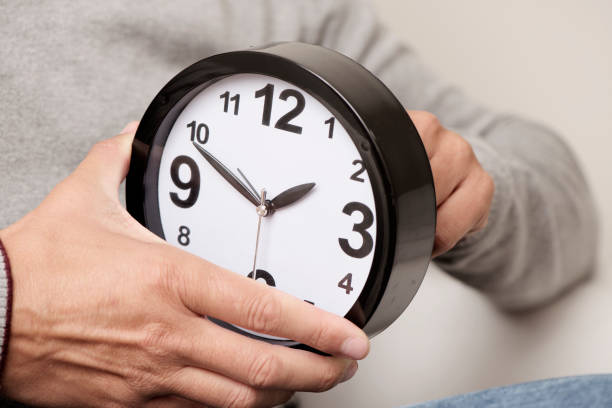 man adjusting the time of a clock stock photo