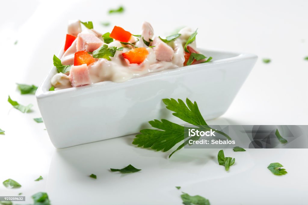 Fresh salad in bowl made from meat, red pepper and mayonnaise Fresh salad in bowl made from meat, red pepper and mayonnaise on white with parsley Appetizer Stock Photo