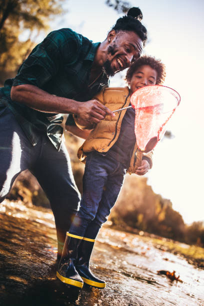istock Father and son in rain boots catching fish in river 923260118