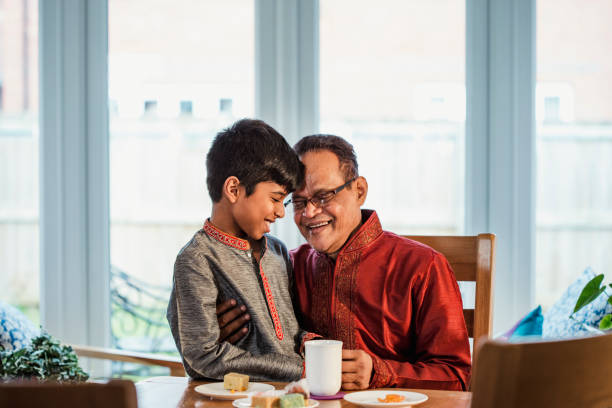 Quality Time with his Grandson A boy wearing a kurta sits and laughs at a dining table with his grandfather who is also wearing a kurta. bangladesh stock pictures, royalty-free photos & images