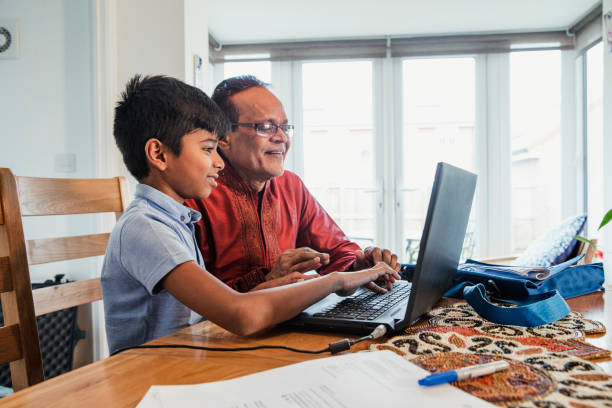 helping his grandson with homework - grandparent using computer laptop dining table imagens e fotografias de stock