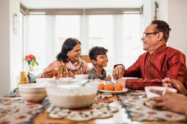 Dinner with his Grandparents A boy wearing a kurta/salwar kameez sits with his grandparents and eats dinner. The senior man also wears a kurta/salwar kameez and the senior woman wears a duppatta. eid ul fitr photos stock pictures, royalty-free photos & images