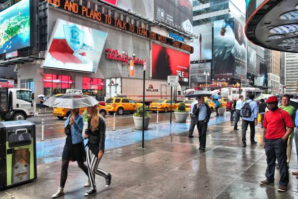 7th Avenue New York: People visit rainy Times Square in New York. The square at junction of Broadway and 7th Avenue has some 39 million visitors anually. walgreens stock pictures, royalty-free photos & images