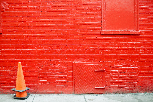 A painted red brick wall with a stack of orange cones.