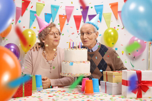 istock Senior couple blowing candles on a birthday cake 923293920