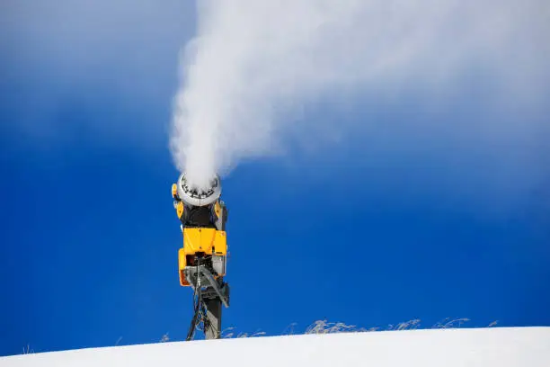 Photo of Snowmaking  with snow gun.  Ski slope artificial snowing. Ski resort  with snow cannon - snow making machine. Beautiful winter nature. Fresh snow on the top of  mountains.  High mountain landscape  Ski area.