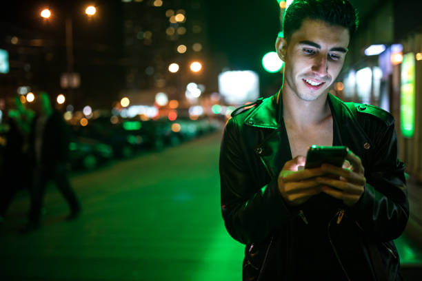 istock Young man using smart phone in city street at night 923301988
