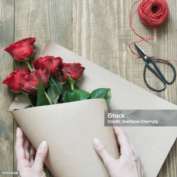 Photo libre de droit de Fleuriste Faire Un Bouquet De Roses Rouges  Enveloppe En Papier Kraft