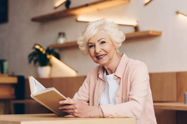 istock senior woman with book in cafe 923314606
