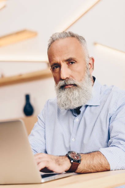 istock senior man with laptop in cafe 923335074