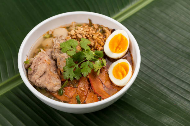 istock Spicy noodle soup with pork and egg in bowl on banana leaf 923363586