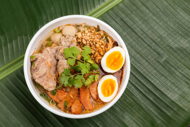 istock Spicy noodle soup with pork and egg in bowl on banana leaf 923363590
