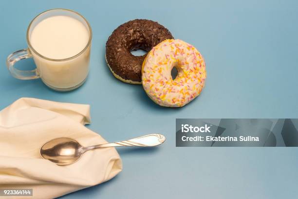 Glasierte Donuts Milch In Eine Glasschale Ein Kleiner Löffel Und Eine Serviette Auf Blauem Hintergrund Stockfoto und mehr Bilder von Blau