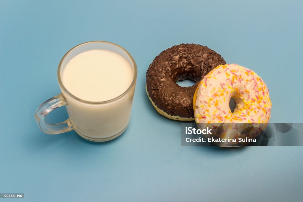 Glasierte Donuts und Milch in eine Glasschale auf blauem Hintergrund - Lizenzfrei Blau Stock-Foto