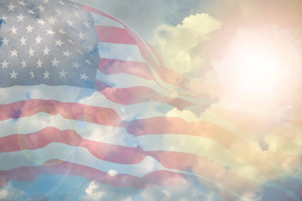 istock USA flag overlay on blue, sunny sky with clouds. 923365134