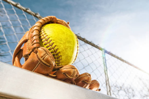 nach oben auf eine gelbe softball im handschuh auf bank mit sonne flare - softball baseball glove sports equipment outdoors stock-fotos und bilder