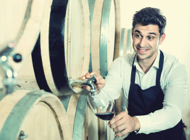 istock Man pouring red wine into glass in alcohol section 923375054