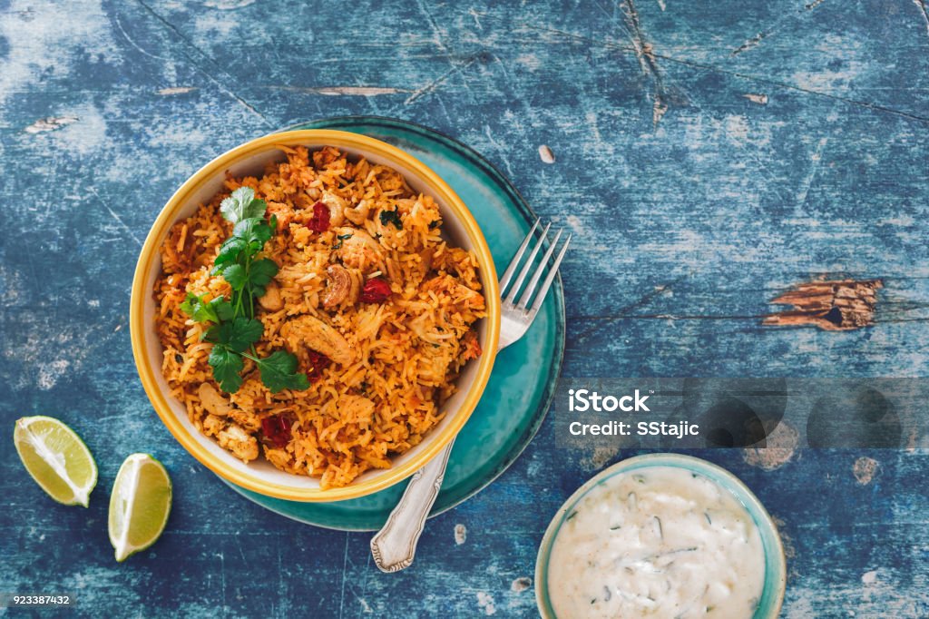 Hyderabadi Chicken Biryani mit Gurken-Raita auf rustikalen Tisch - Lizenzfrei Reis - Grundnahrungsmittel Stock-Foto