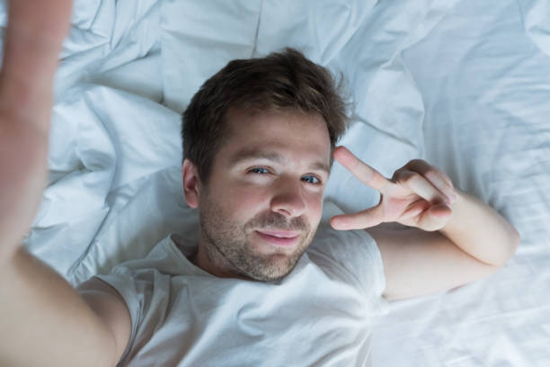 istock handsome man in white shirt taking a selfie in bed 923387766