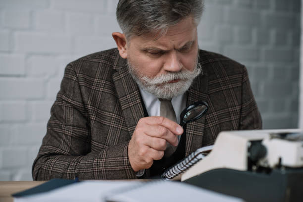 istock bearded senior writer reading manuscript with magnifying glass 923391650