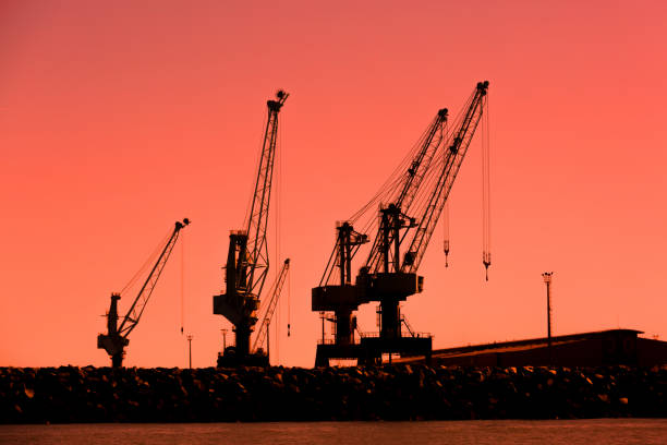 View of Shipyard cranes silhouetted against a beautiful orange sunset.