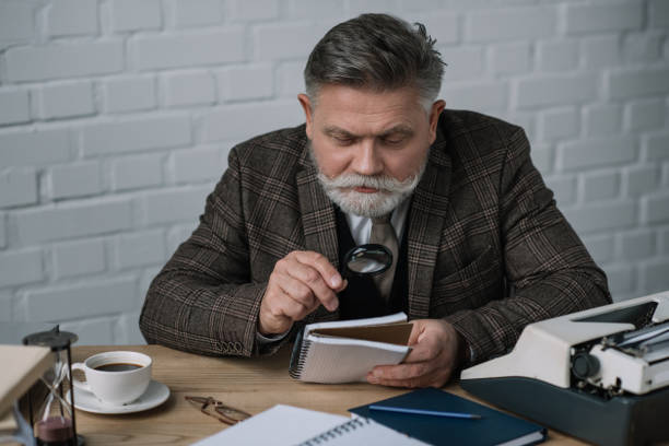 istock handsome senior writer reading manuscript with magnifying glass 923397158