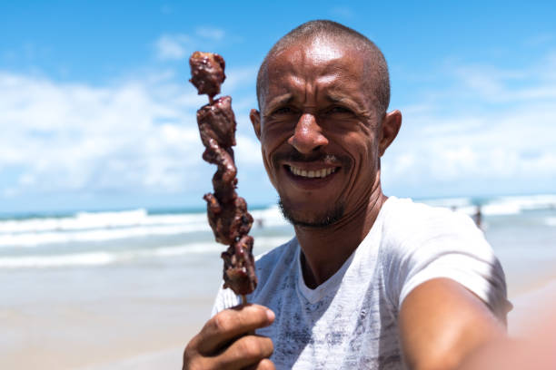 istock Brazilian man holding bbq on a stick on the beach 923397196