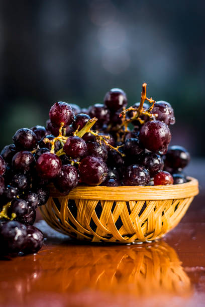 Close up of Grapes,Vitis vinifera in a basket on a brown wooden surface. stock photo