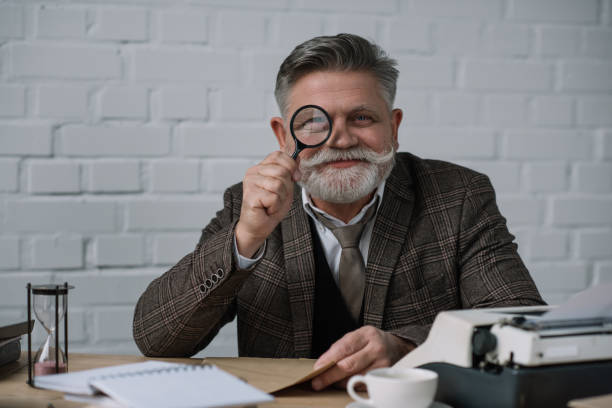 istock senior writer looking at camera through magnifying glass 923402886