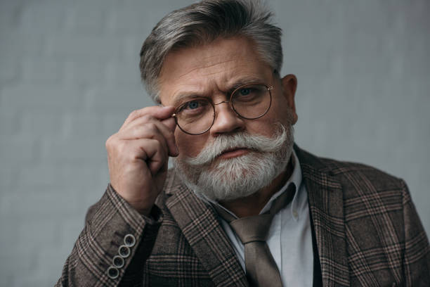 istock serious senior man in tweed suit and glasses looking at camera 923403010