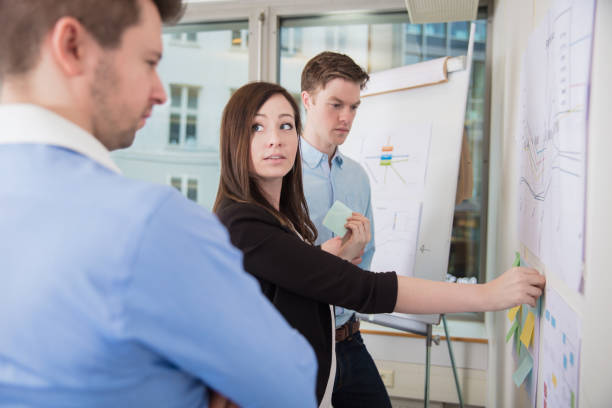 istock Businesswoman Sticking Adhesive Notes While Looking At Male Coll 923405342